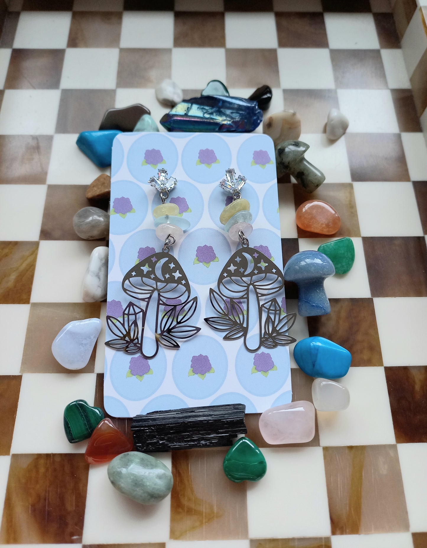 Pair of earrings on a card with decorative stones on a checkered background