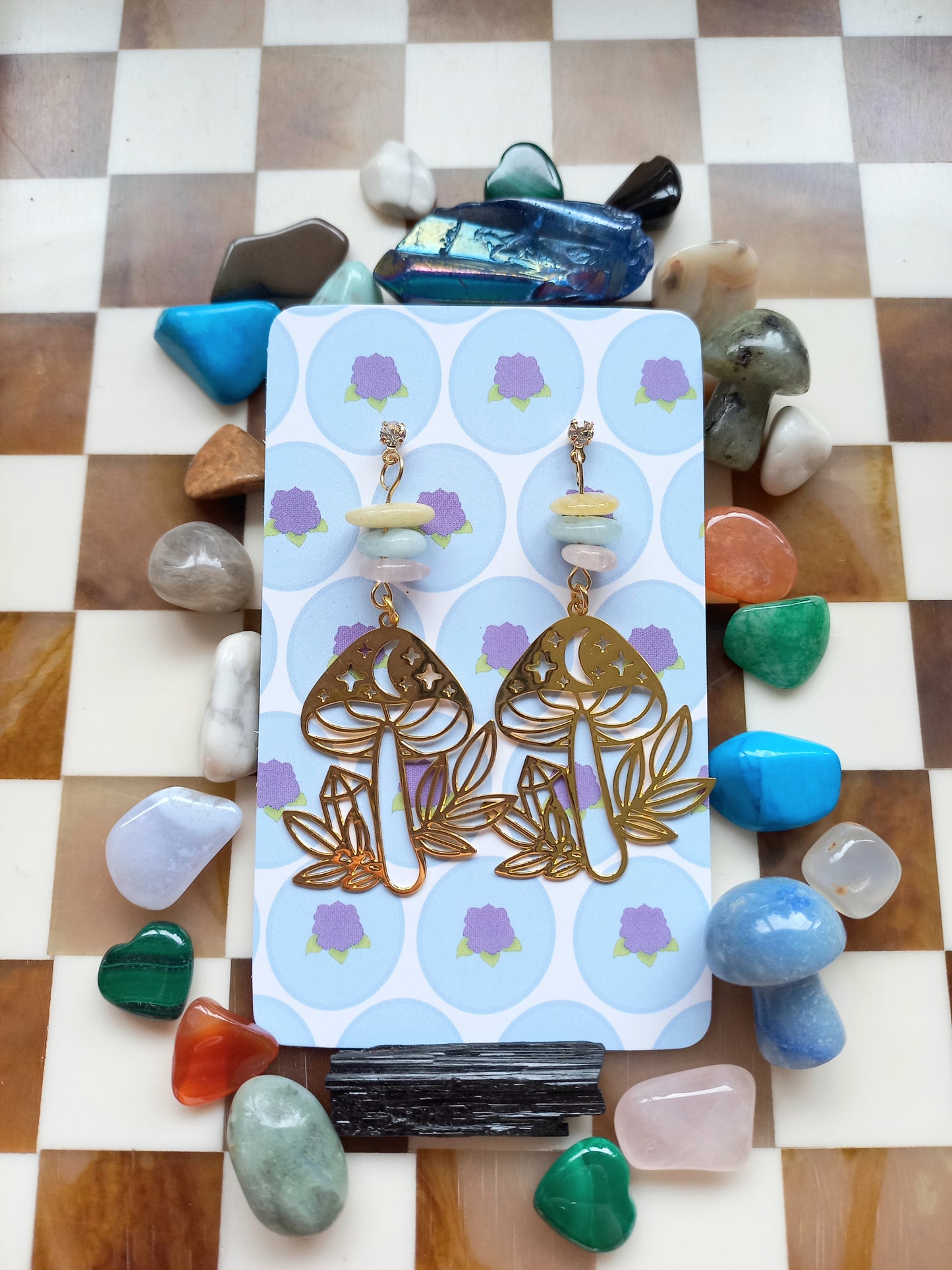 Gold earrings on a card with stones around