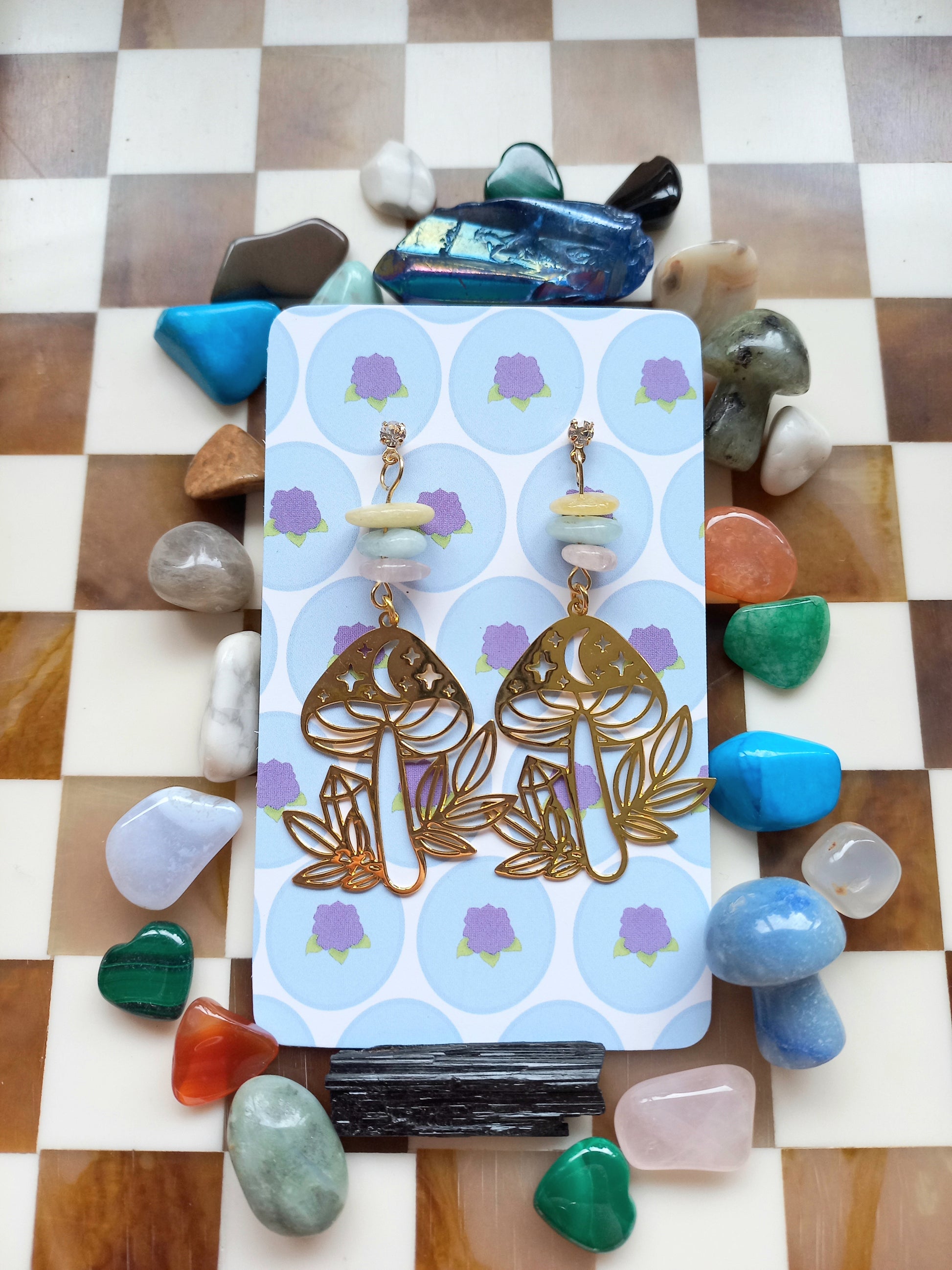 Gold earrings on a card with stones around